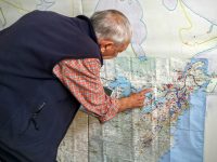 John Andrew points out ski areas he's skiied on a the wall-sized map in his Renton, Wash., home. 
Credit: John Nelson